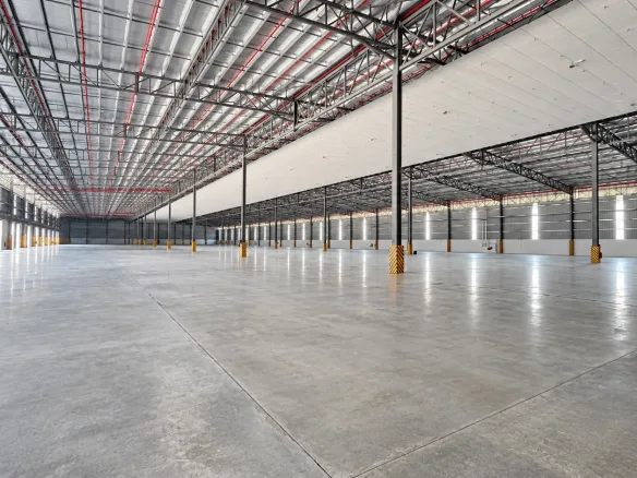 Inside an empty bonded warehouse in Johor, with a steel roof structure, loading doors and a clear concrete floor